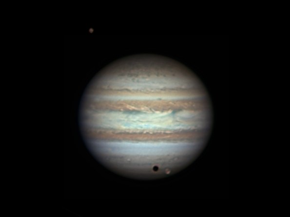 Jupiter with Callisto above, Ganymede and its shadow below