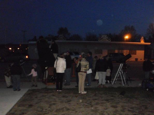 A  crowd gathers to view Saturn and Jupiter.