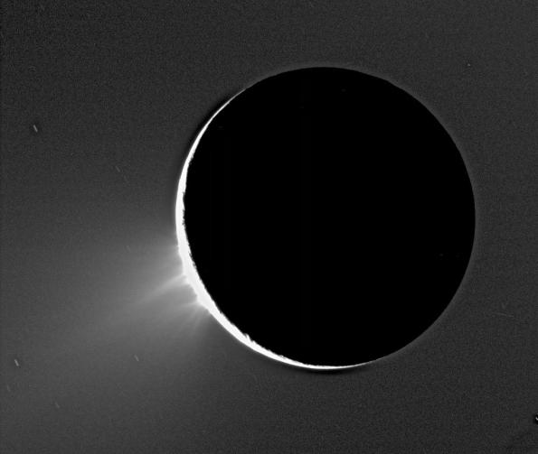 Enceladus' south polar geysers create the E ring. The fine icy particles can only be seen looking back toward the sun. The background is the night face of Saturn, illuminnated by its rings.