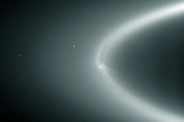 Enceladus, embedded in the E ring of its own making. Taken from the Cassini while in Saturn's shadow.